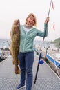 Happy Fisherwoman holding big arctic cod. Norway happy fishing. Woman with cod fish in hands Royalty Free Stock Photo