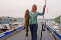 Happy Fisherwoman holding big arctic cod. Norway happy fishing. Woman with cod fish in hands Royalty Free Stock Photo