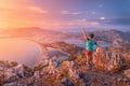 Happy man spread his arms while enjoying stunning view from the top of the mountain to the colorful sea bay and the coast in Royalty Free Stock Photo