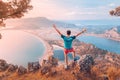 Fit man spread his arms while enjoying stunning view from the top of the mountain to the colorful sea bay and the coast in Royalty Free Stock Photo