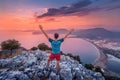 Fit man spread his arms while enjoying stunning view from the top of the mountain to the colorful sea bay and the coast in Royalty Free Stock Photo