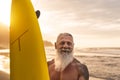 Happy fit senior having fun surfing at sunset time - Sporty bearded man training with surfboard on the beach Royalty Free Stock Photo