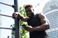 Happy fit sporty young black man using phone standing in workout park. Royalty Free Stock Photo