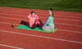 Happy fit teenage girls do situps physical training on athletics track, fitness.