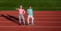 Happy fit girls show thumbs up standing on athletics track, physical fitness and sports promotion