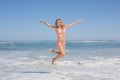 Happy fit woman in bikini jumping on the beach Royalty Free Stock Photo