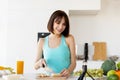 Happy fit woman preparing fruit salad, cutting banana and recording new video for her food blog, standing in kitchen Royalty Free Stock Photo