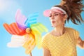 Happy fit woman against blue sky blowing on colorful windmill Royalty Free Stock Photo