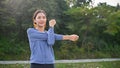 Happy fit young Asian woman stretching her arms, warming up before running in the nature park Royalty Free Stock Photo