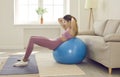 Happy fit young woman doing sit ups on exercise ball during fitness workout at home Royalty Free Stock Photo