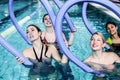 Happy fitness class doing aqua aerobics with foam rollers Royalty Free Stock Photo