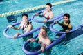 Happy fitness class doing aqua aerobics with foam rollers Royalty Free Stock Photo