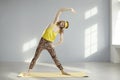 Happy fitness geek doing standing side bend exercise during sports workout in sunny gym