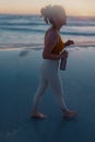 Happy fitness woman jogger walking at beach at sundown