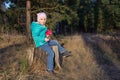 happy five-year-old girl sitting in a jacket on a stump in the woods in the spring