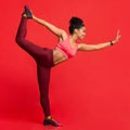 Happy athletic girl in yoga pose over red background