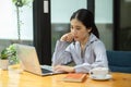 Happy focused asian business woman analysing new strategy and working on her laptop