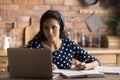 Happy focused female adult student with headphones and laptop