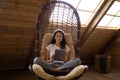 Happy focused Latin woman relaxing in comfortable armchair