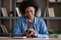 Happy focused young African freelance worker girl using mobile phone Royalty Free Stock Photo