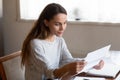 Happy focused young lady reading paper letter with good news.