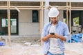 happy foreman builder using smart phone calling business contact in construction site. construction engineer or architect with