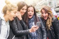 Happy four friends walking on the street and using cellphones