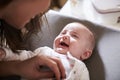 Happy four month old baby boy on changing table looking up at his mum, over shoulder view, close up Royalty Free Stock Photo