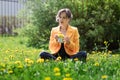 Happy free young woman sitting outdoors on field with flowers and green grass, enjoying spring Royalty Free Stock Photo