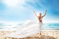 Happy Freedom Woman on Beach Enjoying Sun Arms Outstretched. Rear View of Girl Raised Hands fluttering White Dress on Wind. Summer