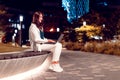 Happy freelancer lady working on laptop, sitting on bench at evening park working outdoors, side view, free space Royalty Free Stock Photo