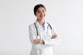 Happy friendly attractive young indian woman doctor in white coat with stethoscope with crossed arms on chest Royalty Free Stock Photo