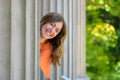 Happy friendly middle-aged woman peering around a pillar