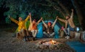 Happy friends celebrate and have fun laughing together with arms raised bonfire on camping Royalty Free Stock Photo