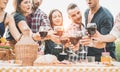 Happy friends cheering at barbecue picnic outdoor - Young people having fun drinking red wine in vineyard winery at sunset -