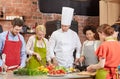 Happy friends and chef cook cooking in kitchen Royalty Free Stock Photo