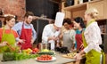 Happy friends and chef cook cooking in kitchen Royalty Free Stock Photo