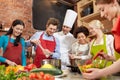 Happy friends and chef cook cooking in kitchen Royalty Free Stock Photo