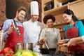 Happy friends and chef cook cooking in kitchen Royalty Free Stock Photo