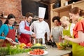 Happy friends and chef cook cooking in kitchen Royalty Free Stock Photo