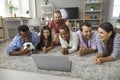 Happy friends diverse group watching football match on laptop lying on floor Royalty Free Stock Photo