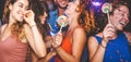 Happy friends doing party dancing in the nightclub - Trendy young people having fun celebrating together with confetti and candy Royalty Free Stock Photo