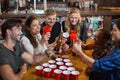 Happy friends drinking beer while sitting around disposable cups in bar Royalty Free Stock Photo