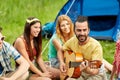 Happy friends with drinks and guitar at camping Royalty Free Stock Photo