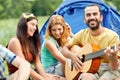 Happy friends with drinks and guitar at camping Royalty Free Stock Photo