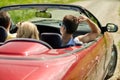 Happy friends driving in convertible car at summer