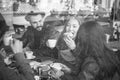 Happy friends eating breakfast and drinking coffee with milk in bar cafeteria - View through glass with reflection - Black and