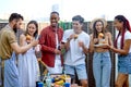 Happy friends eating burgers and drinking lemonade at barbecue patio party