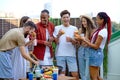 Happy friends eating burgers and drinking lemonade at barbecue patio party