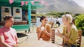 Happy, friends and eating ice cream at outdoor table of restaurant, speaking or funny group bonding. Gelato, people and Royalty Free Stock Photo